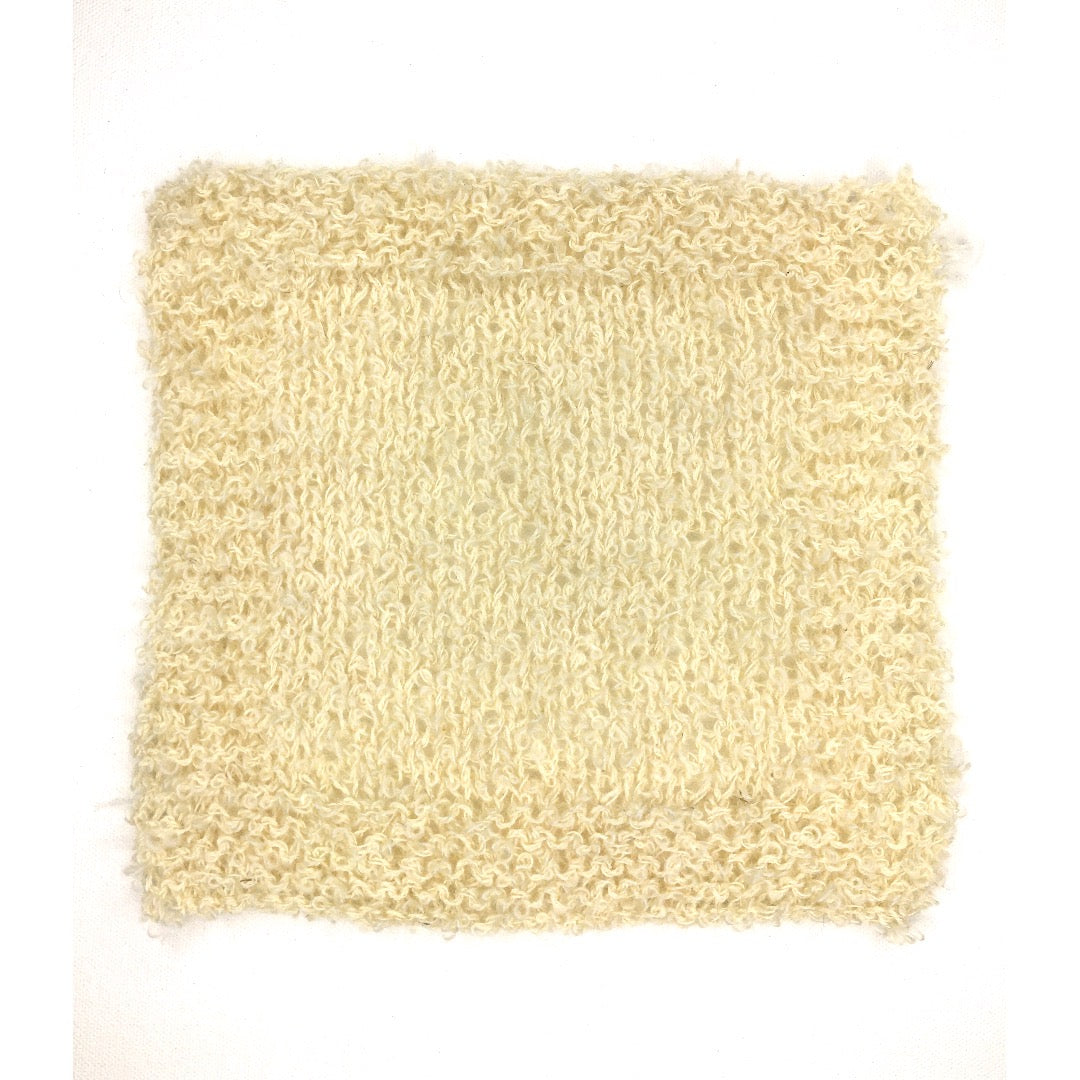 A knitted swatch of soft beige DK Boucle yarn