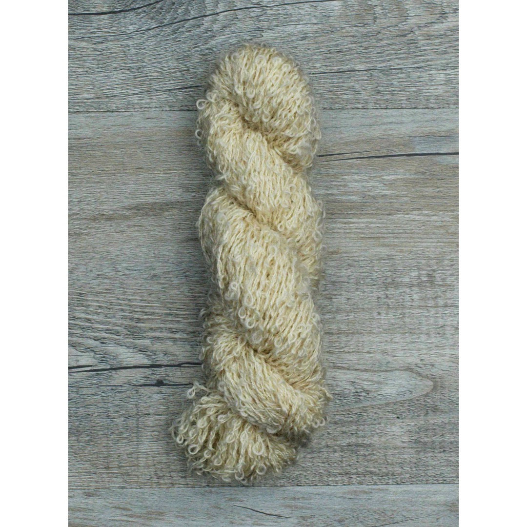 A single hank of soft beige DK Boucle yarn