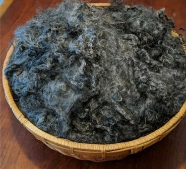 Woven basket filled with washed charcoal mohair locks