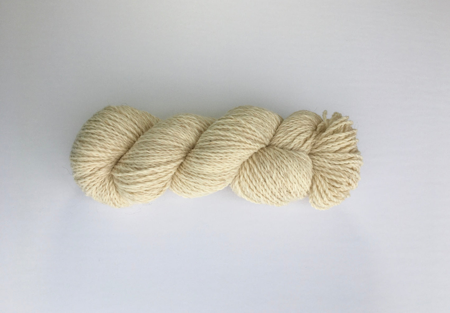 One hank of creamy white Ramo Worsted weight yarn with just a hint of red